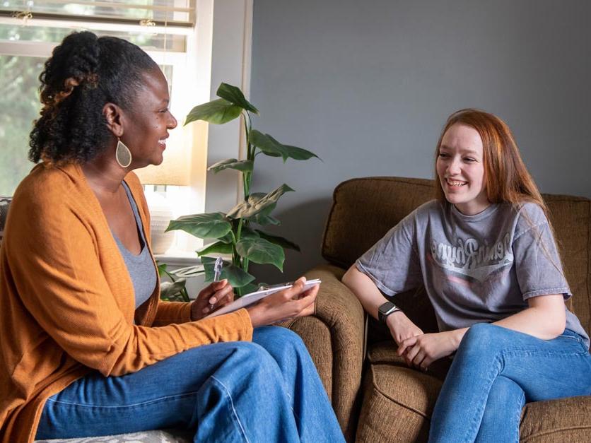 A counselor talks with a student on a couch in her office