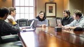 Student investors talk with professor seated around a conference table