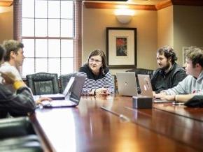 Dr. Lesser with students around a table discussing stocks and the market