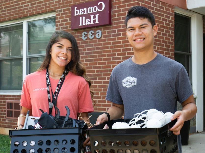 Two students cart boxes into Conrad Hall as part of move in. 